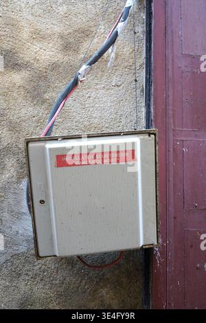 Danger of death sign on an old electrical box with exposed wires on a weathered wall Stock Photo