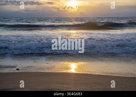Ocean waves breaking on a sandy beach during a beautiful tropical sunset and golden hour, solace, france Stock Photo