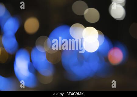 Abstract background featuring blurred blue and gold bokeh lights against a dark night backdrop Stock Photo
