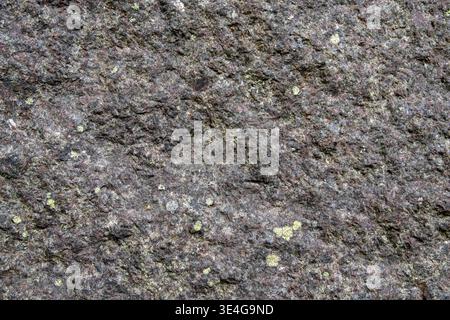Rough dark granite rock surface creating a natural texture background Stock Photo