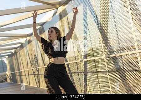 Dancer practicing a modern dance choreography on a pedestrian bridge Stock Photo