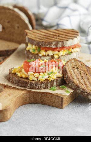 Food, Scrambled eggs and smoked salmon on rye bread with green onions. A sandwich for breakfast. Selective focus Stock Photo