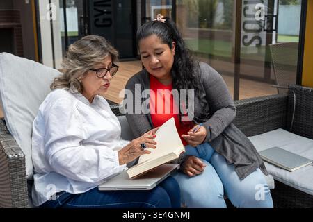Two women of different generations discussing content from an open book Stock Photo