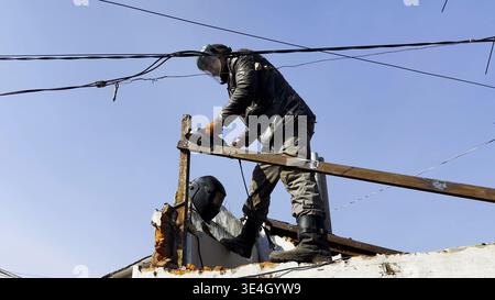 Young mechanic in protective gloves polishing iron using electric grinder wheel at construction. Professional repairman grinding metal details with Stock Photo