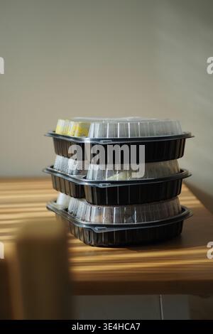 Food containers stacked on a wooden table in a kitchen Stock Photo