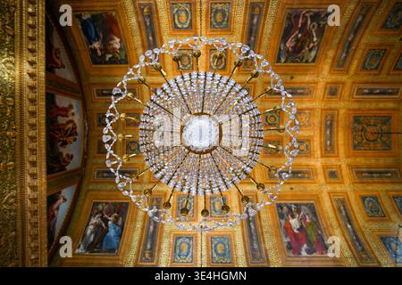 Low angle view of an ornate crystal chandelier and allegorical painted ceiling in the Ballroom Gallery at the Palace of Compiegne, a former royal and Stock Photo
