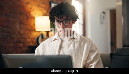 Man, research and laptop in apartment with remote work, glasses and journalist proofreading for story. Freelance writer, person and review article in Stock Photo