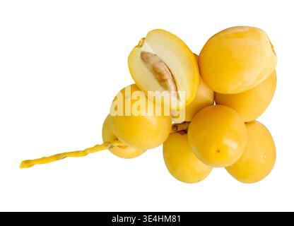 Fresh ripe yellow Barhi date palm fruits in small bunch with a half in stack are isolated on white background with clipping path. Concept of iftar Stock Photo