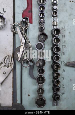 An open tool case with sockets, bits, and a ratchet is shown on a wooden surface, with selective focus on the front tools and a blurred background Stock Photo