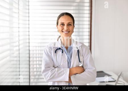 Caucasian female doctor in white coat posing in clinic office Stock Photo
