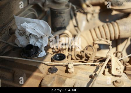 Close view showing dirty dusty car engine covered in thick desert sand awaiting mechanic repair. Neglected motor requires deep maintenance having whit Stock Photo