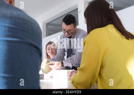 Group of students learning about construction materials during a practical workshop. Engineer demonstrating insulation samples and building systems. C Stock Photo