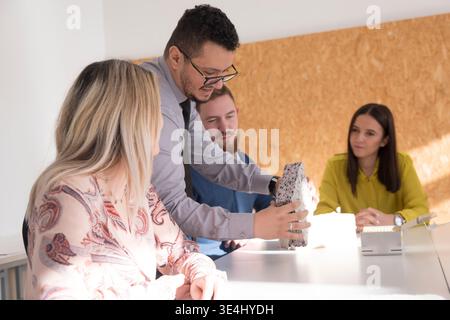 Group of students learning about construction materials during a practical workshop. Engineer demonstrating insulation samples and building systems. C Stock Photo