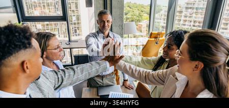 Energetic diverse group celebrates success with teamwork and joy Stock Photo