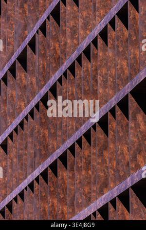 Close-up of modern architecture facade featuring rusted metal panels and sharp diagonal lines. Abstract geometric pattern creates depth, texture, and Stock Photo