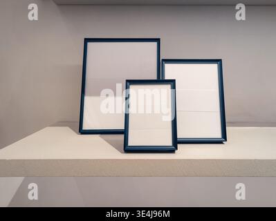 Black frames of various sizes displayed on a white shelf, perfect for a mockup. The sleek, minimalist design is ideal for showcasing artwork, photos, Stock Photo