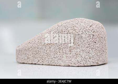 Pumice stone with a rough texture displayed on a reflective surface, showcasing its porous structure and natural color variations for beauty and Stock Photo