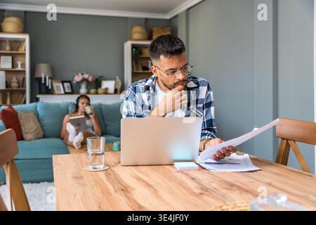 Economic analyst working from home reviewing reports and market predictions for company strategy, focused on oil price surge research while partner re Stock Photo