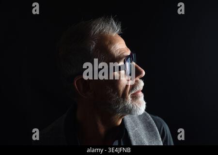 side view of portrait of a mature man look up on black background Stock Photo