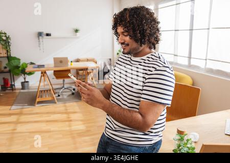 Young Indian man using smartphone while standing Stock Photo
