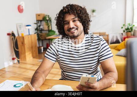 Young Indian man holding smartphone and notebook Stock Photo