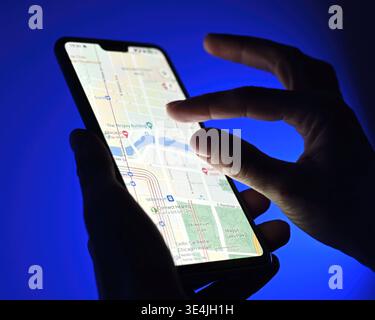 Poznan, Poland - 13 January: Girl using google maps app on a smartphone against blue background, close up view Stock Photo