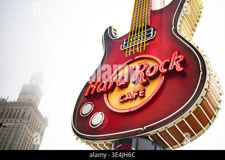 Warsaw, Poland - 29 December 2024: Big Neon Guitar Serves As The Advertising Logo For Hard Rock Cafe Against The Backdrop Of Warsaw's Science And Culture Building Stock Photo