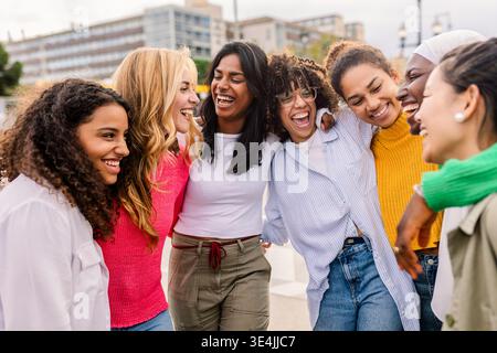 Diverse young women hugging and smiling together outdoors Stock Photo