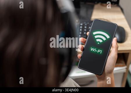 Person holding a smartphone showing a wi-fi signal, representing internet connection and digital life Stock Photo