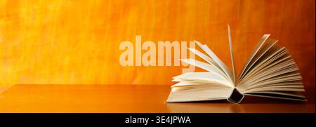 opened book on orange grungy background, opened book on orange grungy background, panoramic, good copy space Stock Photo