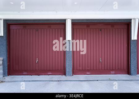Red garage doors stand side by side. Dark stone walls frame the entrance. Concrete steps lead to the doors. Simple, uncluttered, and quiet. Nynashamn Stock Photo