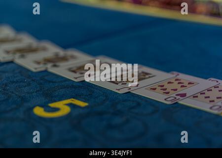 Close-up view of a poker game at a green felt casino table, with soft shadows and muted color palette Stock Photo