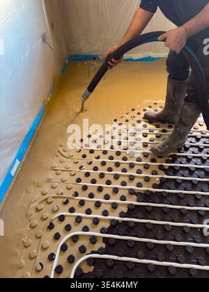 Construction worker installing radiant floor heating with liquid screed Stock Photo
