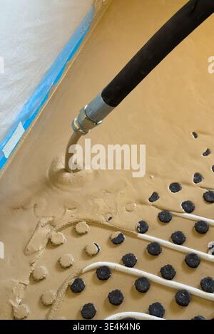 Construction worker installing radiant floor heating with liquid screed Stock Photo