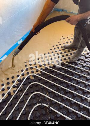 Construction worker installing radiant floor heating with liquid screed Stock Photo