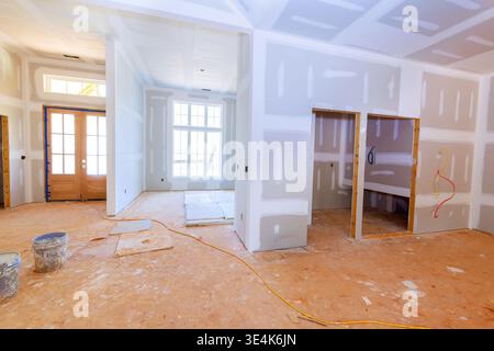 Workers are installing drywall in house under construction with open walls no furniture inside. Stock Photo