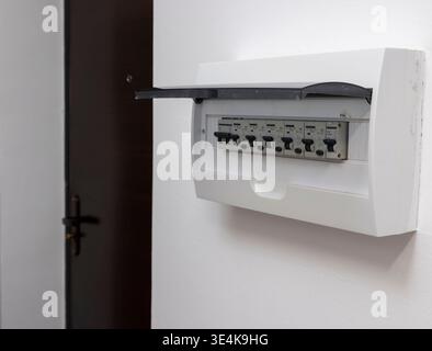 An electrical panel with circuit breakers in an apartment on a white wall near the door Stock Photo