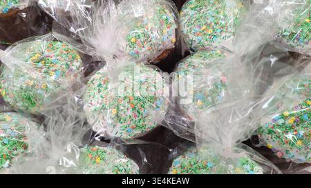Easter cakes in clear packaging with bright sprinkles. Preparing for Easter. Festive baked goods at the store. Close-up of packaged Easter cupcakes. Stock Photo