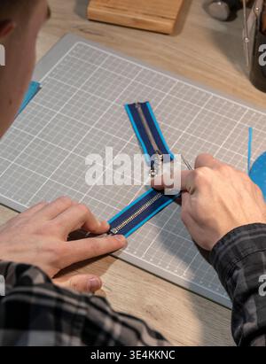 A master tanner works with leather, creating a blue leather bag. The hands of a master leatherworker. Stock Photo