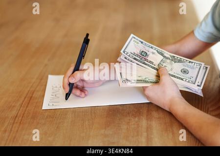 Close up hands holding and counting US dollar banknotes while writing finance on paper. Concept of budgeting, planning expenses, personal finance Stock Photo