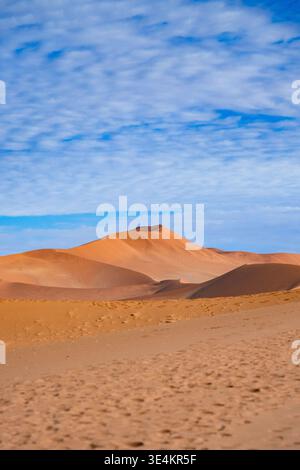 Sinuous Sand Dunes Under Patterned Cloud Sky, Crest And Rippled Slopes Catching Warm Light, Expansive Minimal Stock Photo