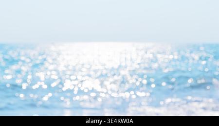 Abstract soft focus view of the sea with sparkling sunlight reflections near the beach in Phuket, Thailand. Clean tropical background with pastel blue Stock Photo