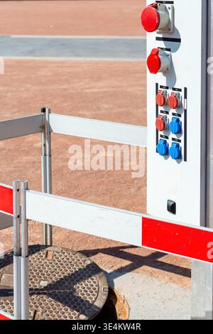 Close side view of a temporary electrical service pedestal with industrial sockets beside a protected utility access point at an outdoor caravan servi Stock Photo