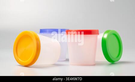 empty translucent plastic containers on gray background, yellow blue red and orange lids with soft focus and copy space, side view of colorful bottles Stock Photo