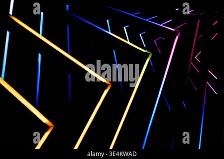Close view of multicolored glowing lines forming angular geometric shapes against a deep black background. Stock Photo