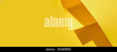 Yellow paper creating abstract shapes and strong shadows, banner format Stock Photo