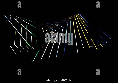 Wide composition of multicolored glowing lines and angular shapes spreading across a black background. Stock Photo