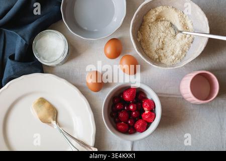 Overhead view of assorted Baking ingredients for making a cake including eggs, strawberries, cherries, coconut oil and gluten free almond and coconut flour Stock Photo
