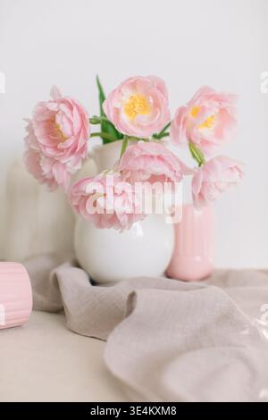 Close-up of a bouquet of Pink peony tulips (double tulips) in a white jug on a table with two ribbed mugs and a linen napkin Stock Photo