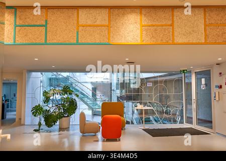 A modern, brightly lit interior lobby or reception area featuring contemporary architectural design. The space showcases white polished flooring and Stock Photo